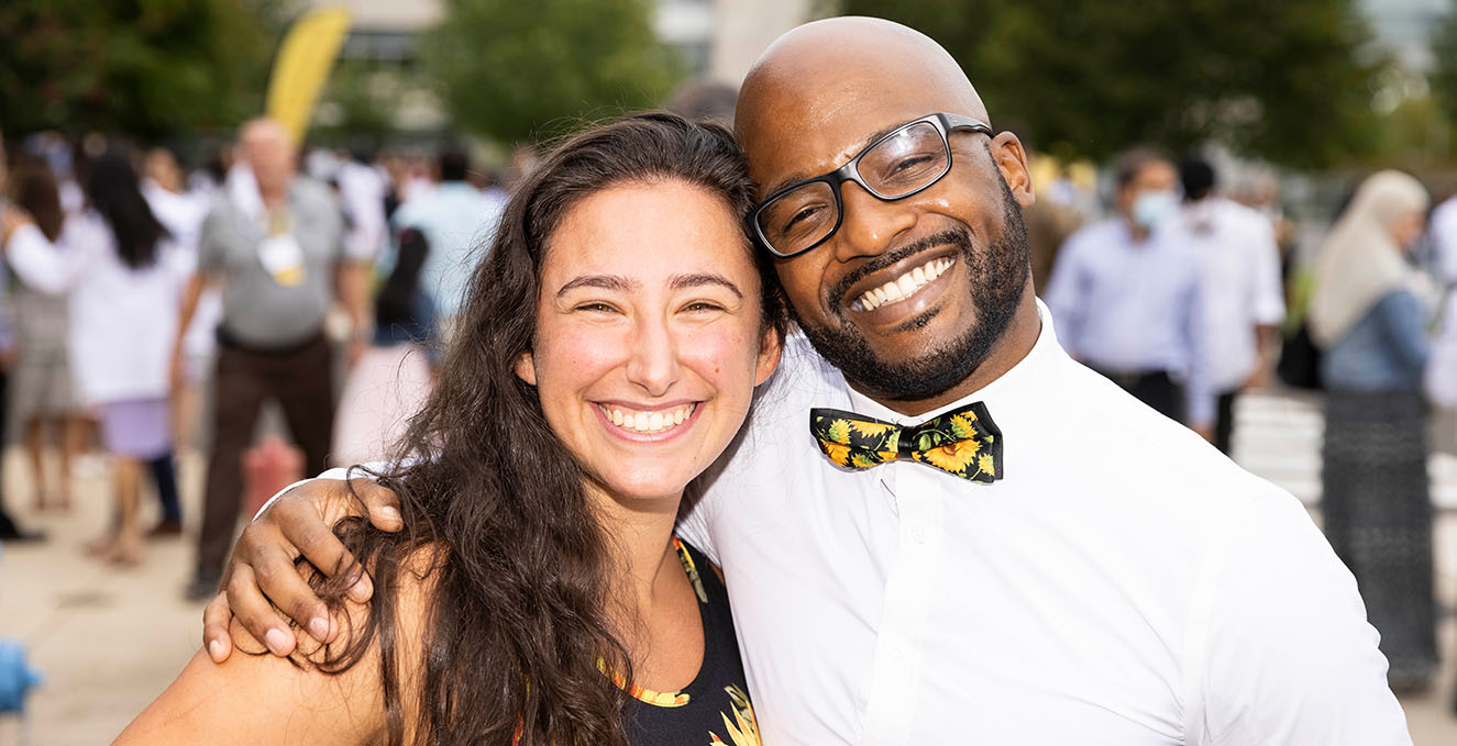 Two SOM students smile and hug at the white coat ceremony